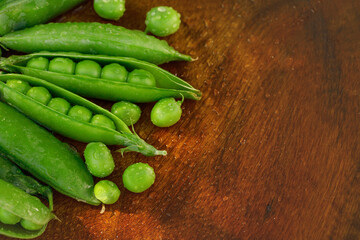 Freshly harvested green peas with droplets on wood background