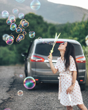 dark-haired girl blows soap bubbles