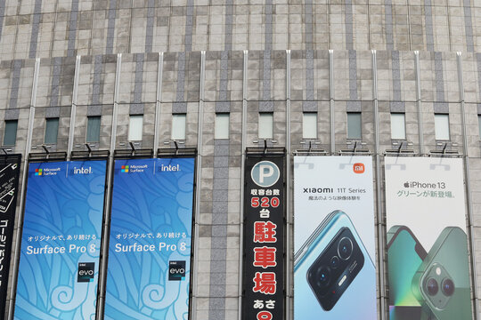 TOKYO, JAPAN - August 14, 2022: Billboards advertising iphones, Microsoft surface pro and Xiaomi smartphones on a Yodobashi Camera store in Tokyo's Akihabara area.