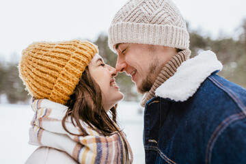 people, love and leisure concept - happy smiling couple touching noses in winter park