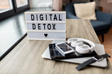 technology concept - digital detox words on light box and different gadgets on blue background - obrazy, fototapety, plakaty