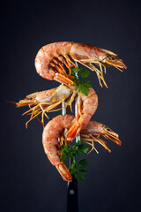 Three boiled tiger prawns or king shrimps with parsley on a fork. Delicious street food idea on...