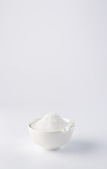 Sugar substitute. Vertical photo of a sugar substitute on a white background in a white bowl. Small spoon in a bowl. Stevia.