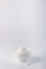Sugar substitute.
Vertical photo of a sugar substitute on a white background in a white bowl. Small spoon in a bowl. Stevia.