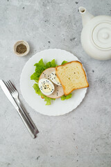 Sandwich with greens, turkey meat and egg on a gray background. Healthy food.
