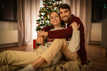 Fototapeta premium holidays, celebration and people concept - happy couple hugging at home on christmas