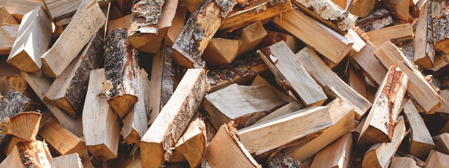 Messy firewood pile in a sunny day, close-up. Web banner.