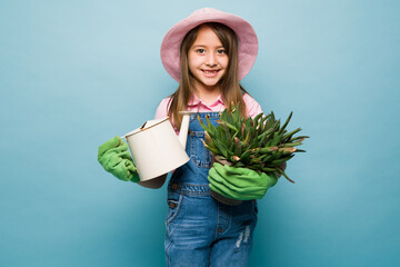 Beautiful happy kid watering her green plants
