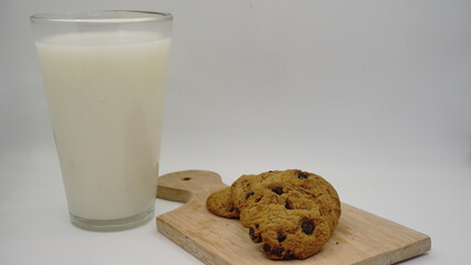 Close up view of glass of milk with cookies on color white background