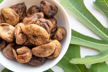 Top view of dried figs with leaves isolated on white wood background