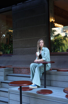 girl in a biret sits at a table with coffee. High quality photo
