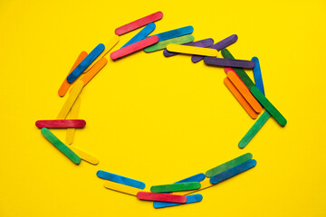 circle of wooden colored sticks on a yellow background. place for text. children's hobby