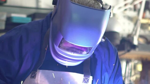 Slowmotion of skillful metal worker working with arc welding machine while wearing safety equipment. Metalwork manufacturing and construction maintenance service by manual skill labor concept.