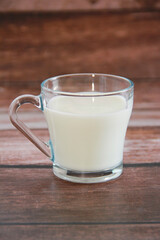 delicious white milk in a transparent glass mug on a wooden background
