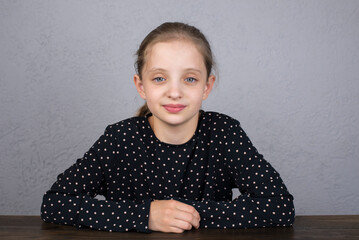 Beautiful girl. Portrait of a European woman 10 - 12 years old. The girl is sitting at the table.