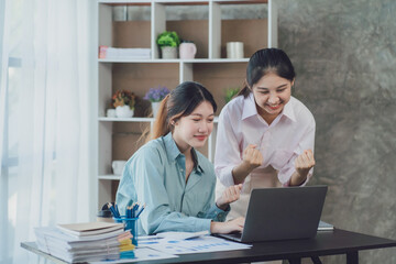 Two young Asian businesswoman discuss investment project working and planning strategy. Business people talking together with laptop computer at office.