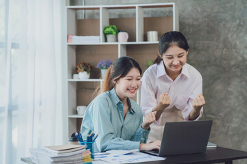 Two young Asian businesswoman discuss investment project working and planning strategy. Business people talking together with laptop computer at office.