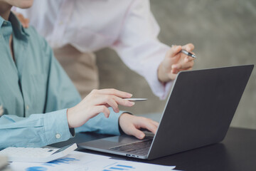Two young Asian businesswoman discuss investment project working and planning strategy. Business people talking together with laptop computer at office.