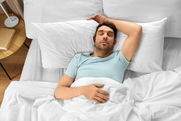 people, bedtime and rest concept - man sleeping in bed at home, top view