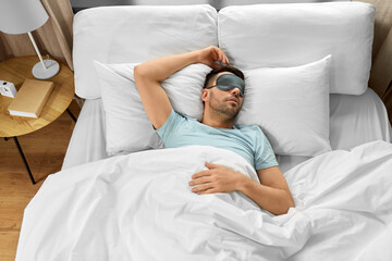 people, bedtime and rest concept - man in eye mask sleeping in bed at home, top view