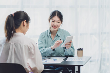 Two young Asian businesswoman discuss investment project working and planning strategy. Business people talking together with laptop computer at office.