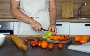 Woman hands are cutting tomatoes on slices. Preparation of pizza.