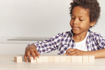 Naklejka premium Kid playing with wooden blocks at home