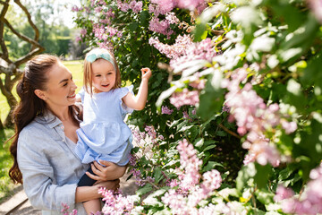Obraz premium family, motherhood and people concept - happy mother with little daughter at summer park or garden