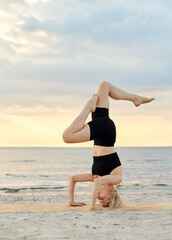 Fototapeta na wymiar fitness, sport, and healthy lifestyle concept - woman doing yoga headstand on beach over sunset