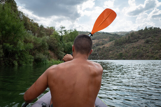 Jovem a praticar desporto com o seu caiaque no rio Tua num dia nublado em Portugal