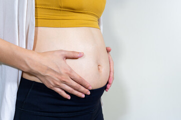 Pregnant woman touching her belly, Third  trimester of pregnancy, Mother show love feeling, Baby is loading, Copy space, Close up.