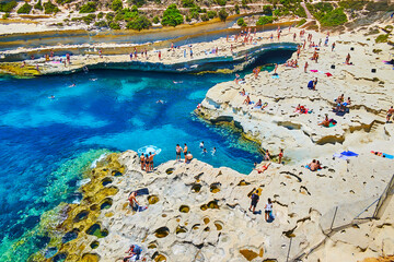 The popular limestone beach of St Peter Pool, Marsaxlokk, Malta
