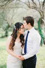 Groom kisses bride on the forehead in an olive grove