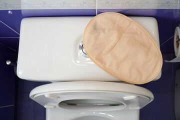 A colostomy bag on top of the toilet. Aerial view. Selective focus.