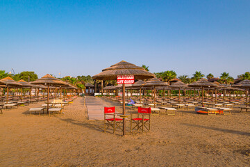 Vieste, Foggia, Italy 26 June 2021 Empty sunbeds and Lifeguard stand on sunrise at Scialara, a sandy sunrise beach 