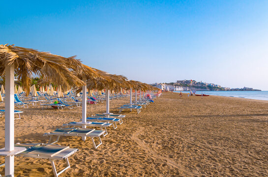 Vieste, Foggia, Italy 26 June 2021 Scialara, a sandy sunrise beach and in background on chalky rocks the oldtown of Vieste and the monolite Pizzomunno