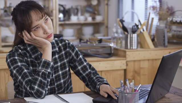 annoyed asian girl student propping face and staring at the monitor is tapping on the keyboard while having problems with her stuck laptop at home.