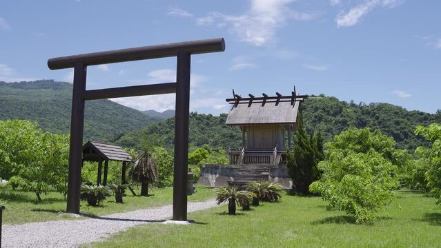 ancient shinto shrine with torii entrance among green meadows against mountains and blue sky at background on a breezy clear day in summer, Luye Taitung, Taiwan