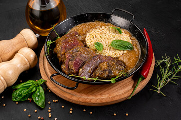 Dish of grilled meat, sauce and rice on wooden background