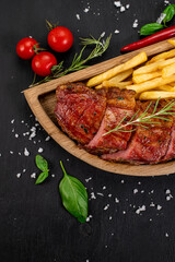 Fried meat steak with french fries and ketchup on wooden background