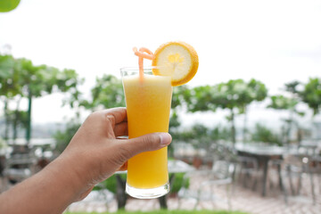 POV of holding a glass of orange juice in nature 