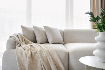 Pillows and blanket on modern soft grey sofa