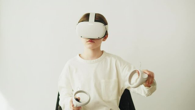 Boy using virtual reality glasses with controllers, playing video games, child gamer wearing new generation gaming headset for entertainment and education, future technology concept.
