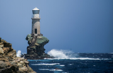 lighthouse in andros island greece in day light and sea waves