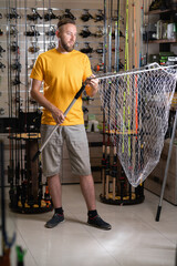 Fisherman choosing a landing net in a fishing shop.