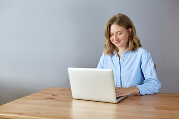 Close up portrait of a beautiful young woman smiling and looking at laptop screen.