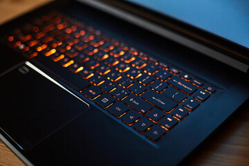 Laptop keyboard with orange neon illumination, backlit keyboard.