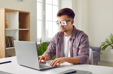 Tired sleep deprived overworked depressed lazy bored unproductive inefficient man pretends to work or study on laptop computer, lacks energy and hides his tiredness by wearing fake eye sticker glasses