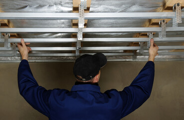 Man assembles profile metal frame for plasterboard