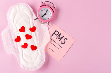 Women's Menstrual pads (sanitary napkin) with red hearts, PMS inscription and alarm clock on a pink...